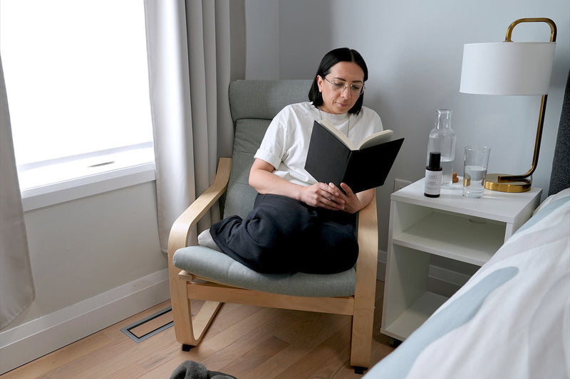 Woman reading beside bed.