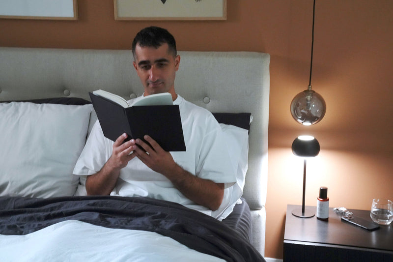 A man reading a book in bed.
